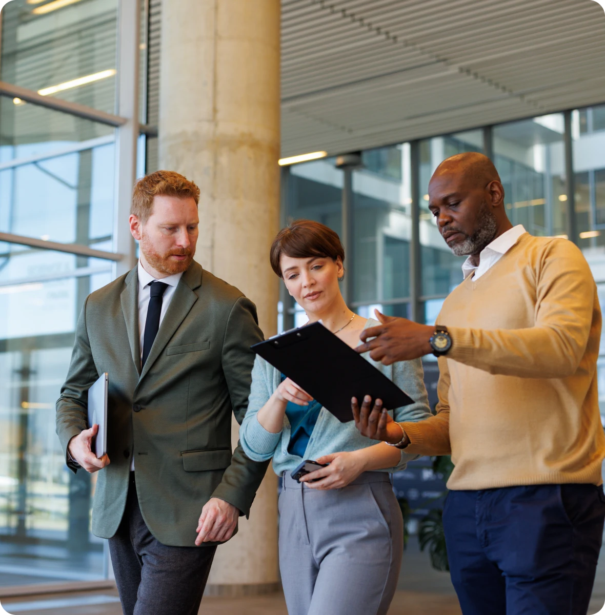 Three business people walking down a hallway, two men and a woman